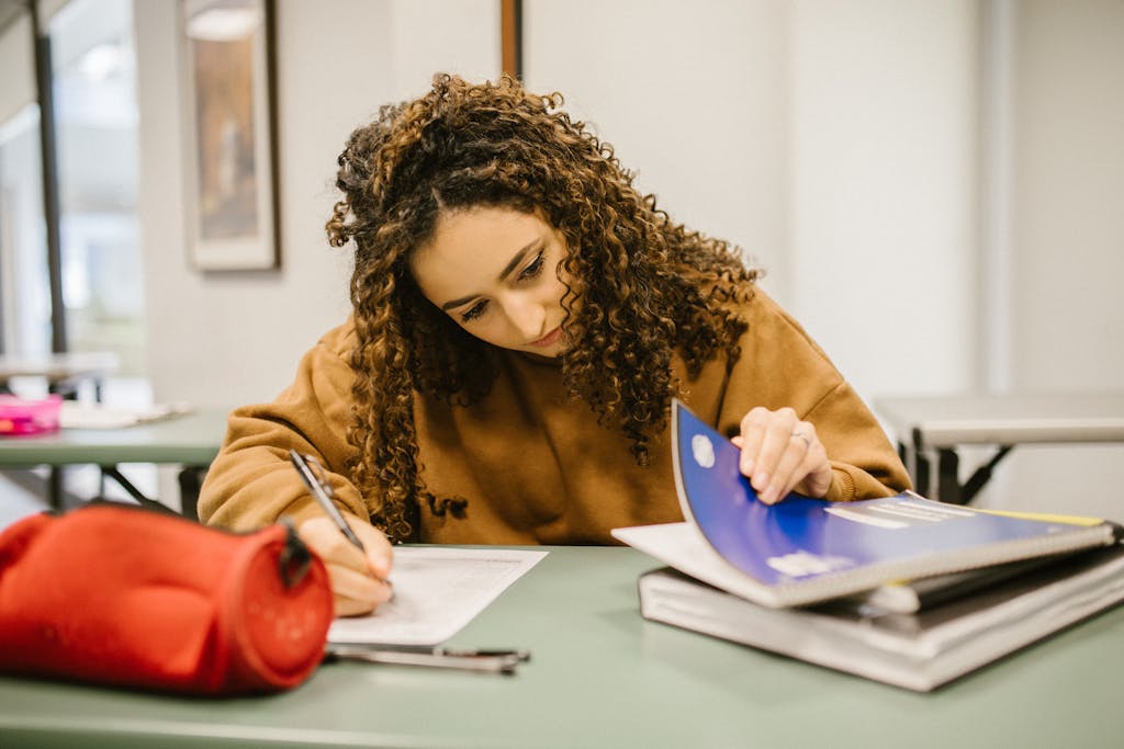 BLOG VIEW Naijastudyhub A college student studying diligently at a desk with textbooks and notes.