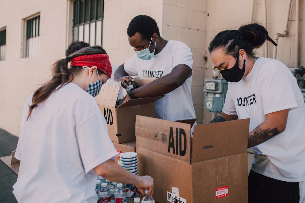 BLOG VIEW Naijastudyhub Volunteers with masks packing aid boxes with supplies outdoors during the day.